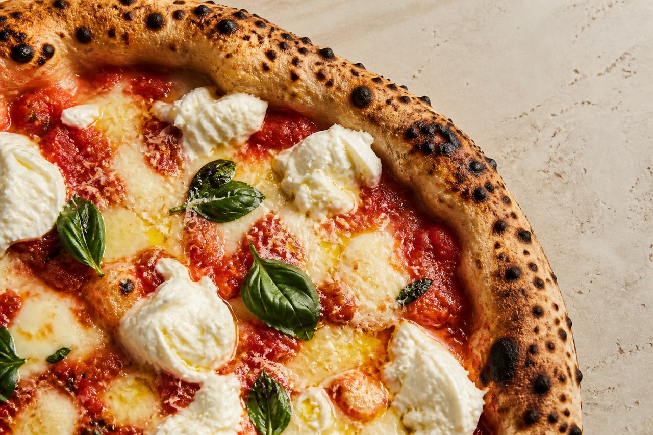 Stämningsbild av pizza med tomat, mozzarella och basilika